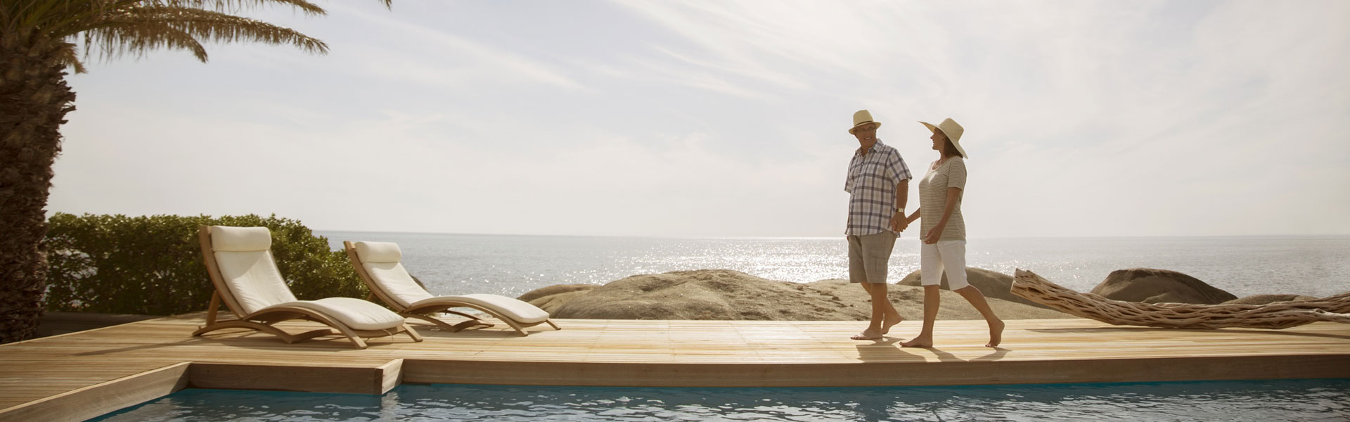 Retired couple walking along the ocean and pool